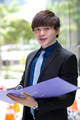 Image showing Young Asian business executive in suit holding file