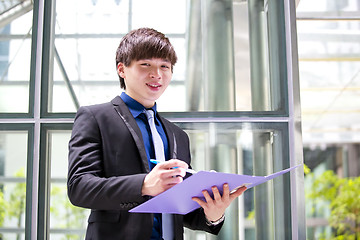 Image showing Young Asian business executive in suit holding file