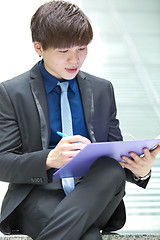 Image showing Young Asian business executive in suit holding file