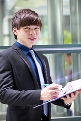 Image showing Young Asian business executive in suit holding file