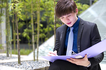 Image showing Young Asian business executive in suit holding file