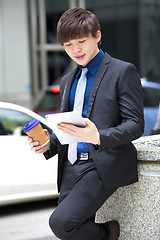 Image showing Young Asian business executive in suit holding tablet and coffee