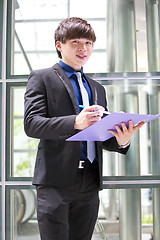 Image showing Young Asian business executive in suit holding file