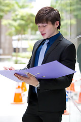 Image showing Young Asian business executive in suit holding file