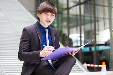 Image showing Young Asian business executive in suit holding file