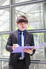 Image showing Young Asian business executive in suit holding file