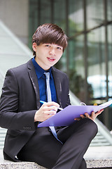 Image showing Young Asian business executive in suit holding file