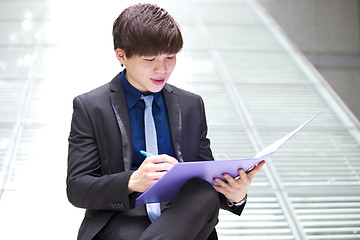 Image showing Young Asian business executive in suit holding file
