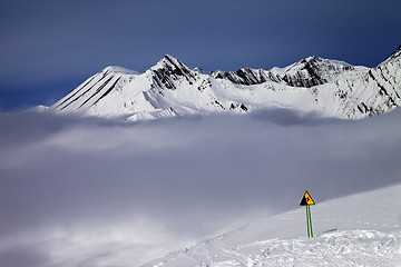 Image showing Warning sing on ski slope and mountains in fog