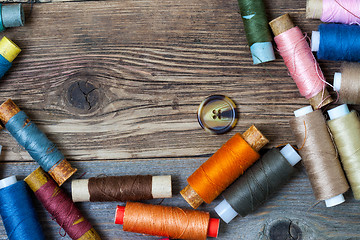 Image showing one vintage button and coils of colored threads