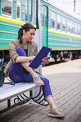 Image showing beautiful woman traveler taking notes in a notebook