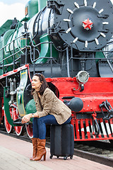 Image showing pretty woman sitting on a suitcase on railroad station