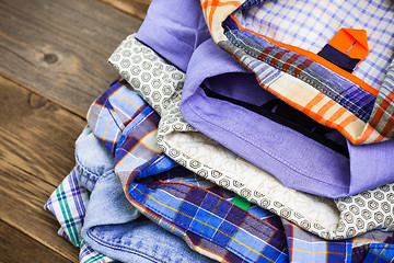 Image showing stack of colored cotton shirts on a wooden shelf