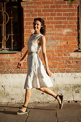 Image showing pretty tanned middle-aged woman in a white dress