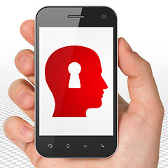 Image showing Learning concept: Hand Holding Smartphone with Head With Keyhole on display