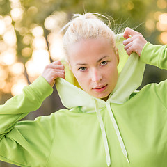 Image showing Confident sporty woman wearing fashionable green hoodie. 