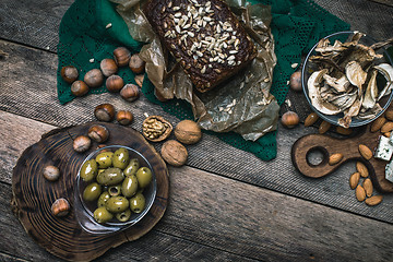 Image showing healthy olives, nuts mushrooms  and bread on wood