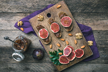 Image showing Sliced figs, nuts and bread with jam on wooden choppingboard
