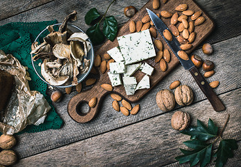 Image showing Sheep cheese, nuts mushrooms on wooden table