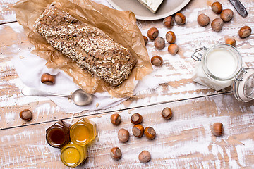 Image showing Bread with honey huzelnuts and cheese on wooden board