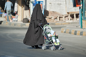 Image showing Arabic woman in hijab conducts carriage with child