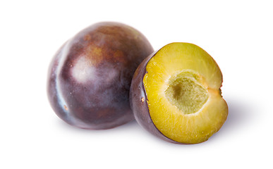 Image showing Whole and half of violet plums near