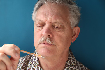 Image showing Ill senior checks his fever.	