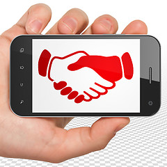 Image showing Political concept: Hand Holding Smartphone with Handshake on display