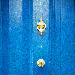 Image showing  blue handle in london antique brown door  rusty  brass nail and