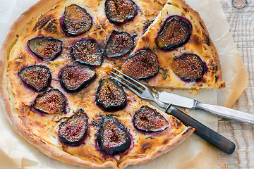 Image showing Sliced pizza with figs, fork and knife.