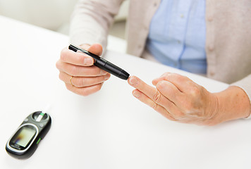 Image showing senior woman with glucometer checking blood sugar