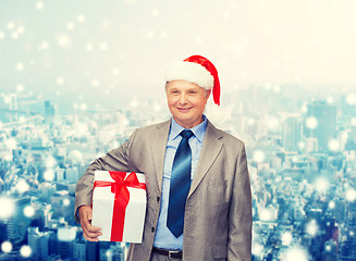 Image showing smiling man in suit and santa helper hat with gift