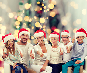 Image showing happy family in santa hats showing thumbs up