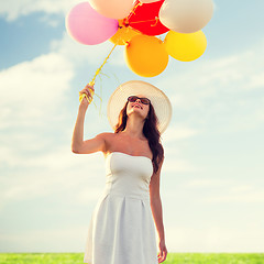 Image showing smiling young woman in sunglasses with balloons