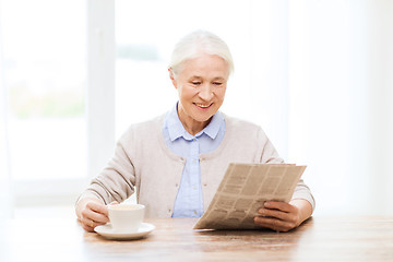 Image showing senior woman with coffee reading newspaper at home