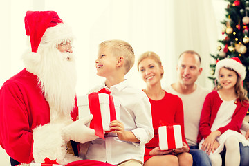 Image showing smiling family with santa claus and gifts at home