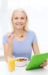 Image showing smiling woman with tablet pc eating breakfast 