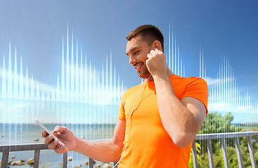 Image showing smiling young man with smartphone and earphones