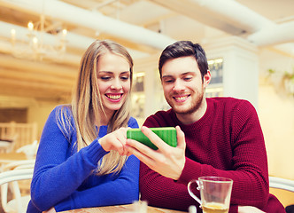Image showing smiling couple with smartphone drinking tea