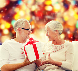 Image showing happy senior couple with gift box at home