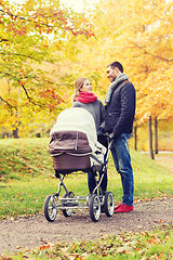 Image showing smiling couple with baby pram in autumn park