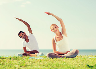 Image showing smiling couple making yoga exercises outdoors