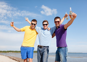 Image showing happy friends with beer bottles on beach