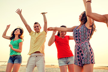 Image showing smiling friends dancing on summer beach