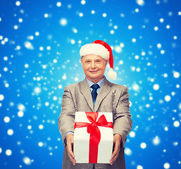 Image showing smiling man in suit and santa helper hat with gift