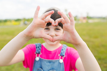 Image showing happy little girl making heart shape gesture