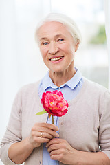 Image showing happy smiling senior woman with flower at home