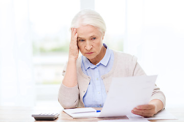 Image showing senior woman with papers and calculator at home