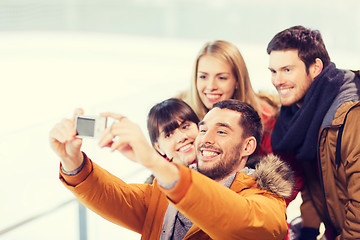 Image showing happy friends with camera on skating rink