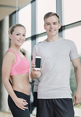 Image showing smiling young woman with personal trainer in gym